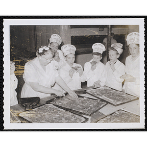 Members of the Tom Pappas Chefs' Club sample baked goods from sheet pans in a kitchen