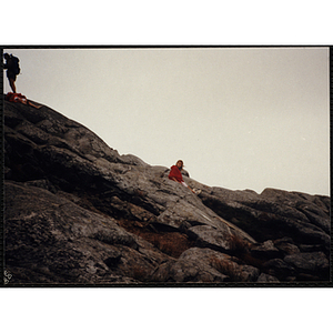 A girl sits on the side of a mountain in the White Mountain National Forest