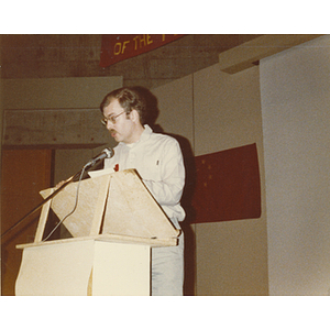 Man speaks at the podium at the 30th anniversary celebration of the People's Republic of China held in the Josiah Quincy School auditorium