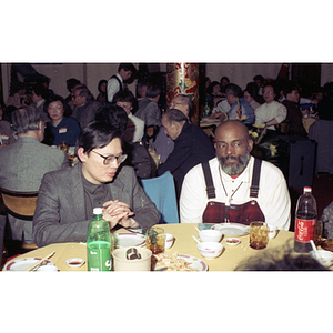 Mel King sits at a restaurant table next to another man during a celebration of the Chinese New Year