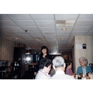 Woman walks past a table of diners at a restaurant for a celebration of the Chinese New Year, hosted by the Chinese Progressive Association