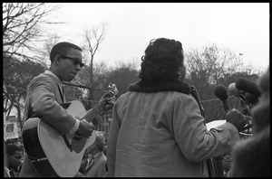 Fannie Lou Hamer singing at the microphones, accompanied by a guitarist, during a civil rights demonstration, in front of the White House on Lafayette Square