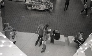 Commune member distributing Free Spirit Press in an indoor shopping mall: image of magazine distributors in reflection