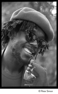 Peter Tosh: portrait wearing beret, dark glasses, and smoking a pipe