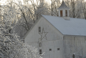 Barn with center cupola and Christmas star amid ice-covered trees