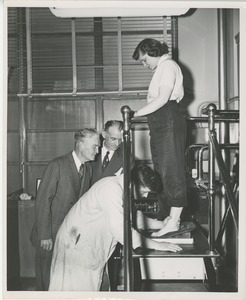 A technician makes a mold of a woman's foot for a prosthetic device as two men, including Bruce Barton, look on