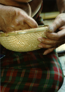 Cambodian basket maker Em Yung at home, weaving a bamboo basket