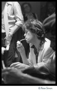 Mick Jagger lighting up a marijuana cigarette backstage at Saturday Night Live, with Peter Tosh partly visible in foreground