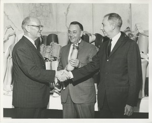 James Burrows shakes a man's hand in front of a 1964 Prosthetics and Orthotics training graduate