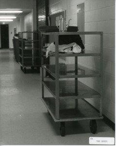 Photograph of a cart with kitchenware stationed along a wall, [1982-1983].