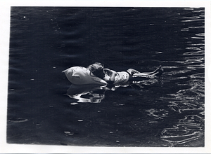 Child lying in a pool float in water in Boston Common
