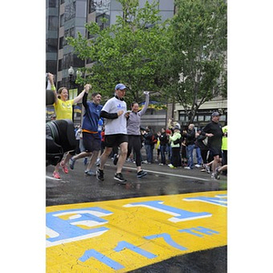 Three runners holding hands as they cross the finish line at Copley Square (#OneRun)