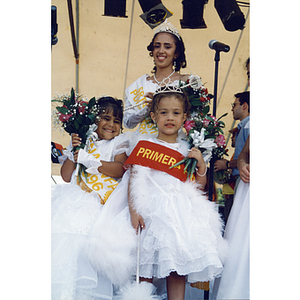 Miss Festival Puertorriqueño, Yaritza Gonzalez, and two young girls wear dresses and hold flowers