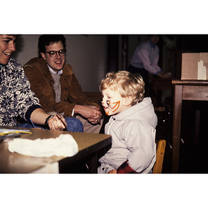 Adults looking at young child with face paint