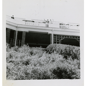 Two men standing on a balcony and waving their hands for the camera during a Board of Overseers meeting