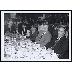 Three men and two women seated around a table, posing at a St. Patrick's Day Luncheon