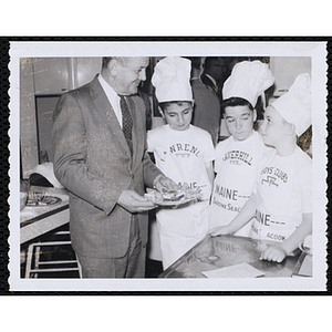 Members of the Tom Pappas Chefs' Club stand next to an unidentified man holding a plate of food