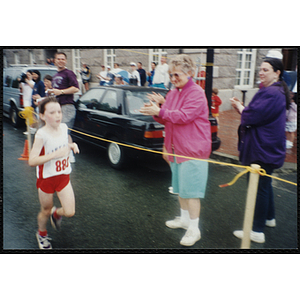 A girl runs past cheering spectators during the Battle of Bunker Hill Road Race