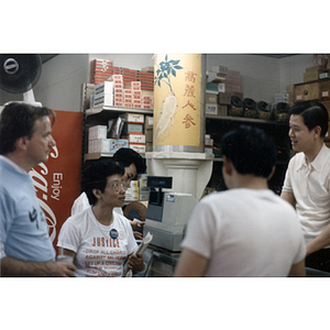 Suzanne Lee talks with a store owner about the Long Guang Huang assault case against the Boston Police Department