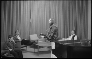 Judy Collins playing guitar, with Susan Evans (her drummer, far left) and Michael Sahl (pianist, right) listening in