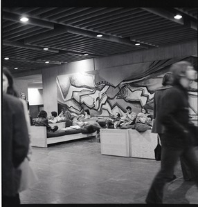 Students sitting in the basement of the UMass Amherst Campus Center, a large abstract painting as backdrop