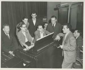 Rosa Rios playing a piano while a group of men look on