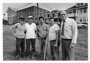 Group of unidentified men standing in a fenced park