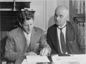 Suffolk University President Gleason L. Archer (1906-1948) looks on as radio personality Rudy Vallee enrolls in Suffolk University Law School