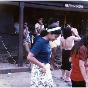 Latino youths stand outside of a refreshment stand adjacent to an unidentified park and lake, while on a summer day trip sponsored by La Alianza Hispana.