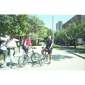 Two men on bicycles, one of them a policeman, pause near the Jorge Hernandez Cultural Center.