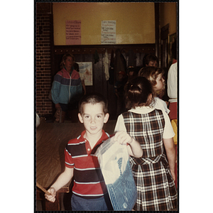 A Young boy holding his new shirt while attending an open house