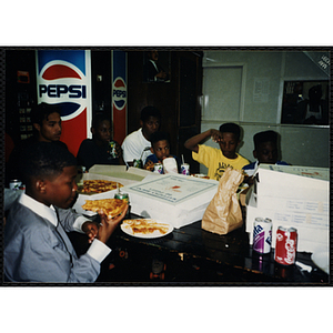 Children sit at a table eating pizza at the Tri-Club youth leadership event at the Roxbury Clubhouse