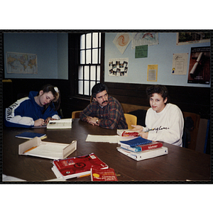 A man sits at a table with two girls at the Tri-Club youth leadership event at the South Boston Clubhouse