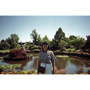 Young woman poses in front of a lily pond in a botanical garden