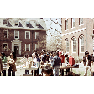 Young people stand around a picnic table surrounded by unidentified brick buildings