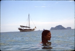 Sandi Sommer swimming, with boat and offshore karst in background