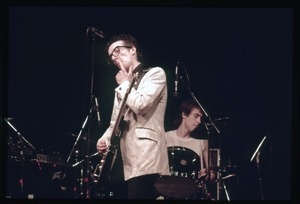 Elvis Costello and the Attractions in concert: Costello on guitar, drummer Bruce Thomas in background