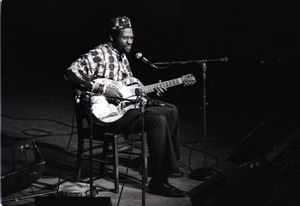 Taj Mahal in concert at Northfield, Mass.: Taj Mahal seated, playing steel guitar