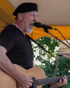 Richard Thompson: half-length portrait with guitar, singing, on stage at the Clearwater Festival