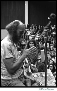 Ram Dass, bowing his head, on stage during an appearance at the College of Marin