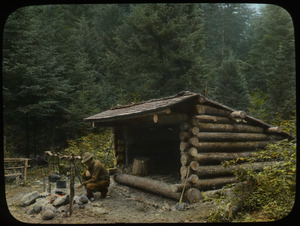 Man cooking over campfire in front of Adirondack log shelter