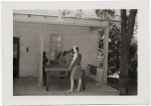 Marjorie Merrill playing ping pong with children on porch of Rust Avenue house rented by the Congress of Federated Organizations (COFO)