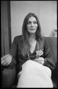 Judy Collins: three-quarter length portrait,seated in a chair with spray of flowers