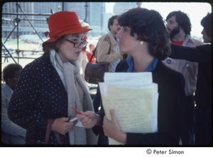 MUSE concert and rally: Bella Abzug in red hat speaking with unidentified woman