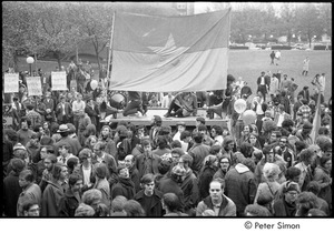 MIT war research demonstration: demonstrators mounting a large NLF flag on a platform, counter-protestors holding signs upper-left