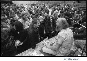 Ram Dass seated on stage at the College of Marin, talking to audience members