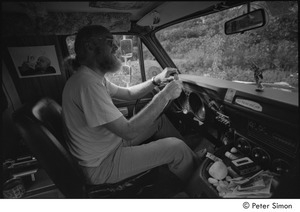 Ram Dass in his van: Ram Dass in the driver's seat with a picture of of Neem Karoli Baba behind him