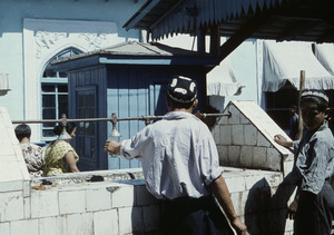 Man filling glass at public fountain