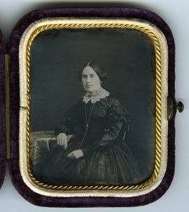 Emily A. Scott Cleveland: three-quarter length studio portrait seated at a table, in velvet covered case