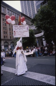 Man dressed as Pope Unpious I marching in San Francisco Pride Parade, carrying sign: 'Pope Pious I of San Francisco... says yes to safe sex/ condoms, human rights, alternative lifestyles'